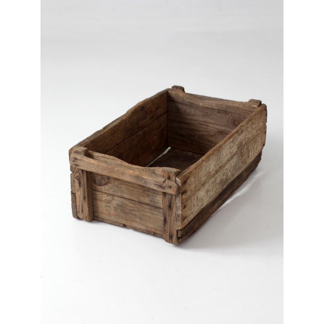 This antique wood farm crate, circa 1920s, features a long rectangular form crafted from rough-hewn boards with exposed...