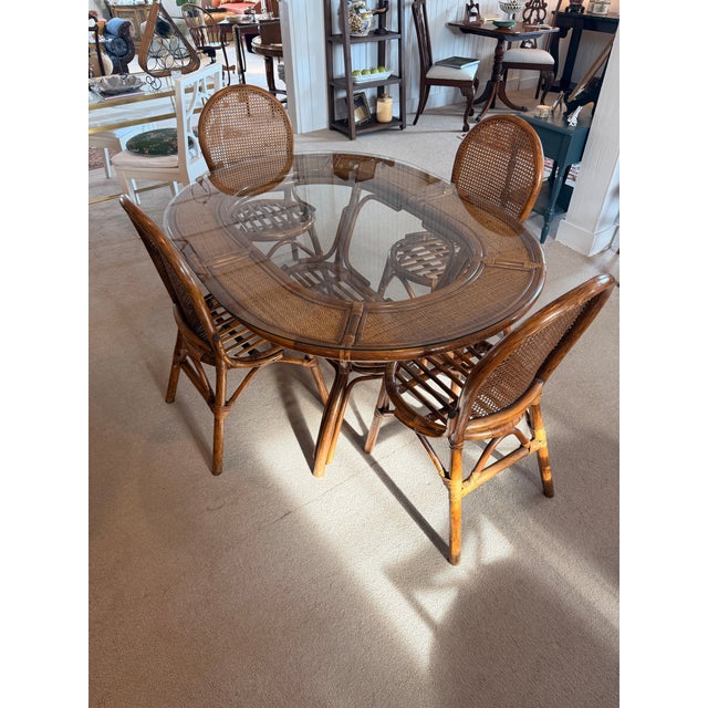 A fabulous vintage bamboo and rattan dining set! The table is oval with a glass top; six chairs with cane backs and bamboo...