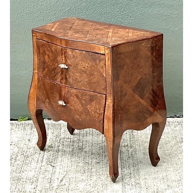 This exquisite petite commode is a fine example of Italian artisanal craftsmanship, featuring a striking parquetry inlay...