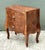 This exquisite petite commode is a fine example of Italian artisanal craftsmanship, featuring a striking parquetry inlay...