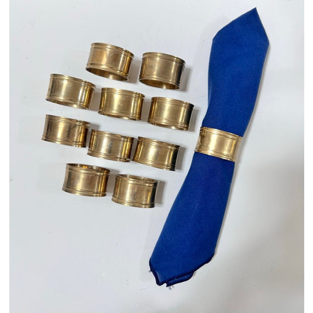 Set of 11 solid brass napkin rings with wide, smooth bands and raised rims. Made in India, with original paper labels...