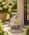 A sculptural vintage garden pedestal featuring three stylized dolphins arranged around a central support, cast in concrete...