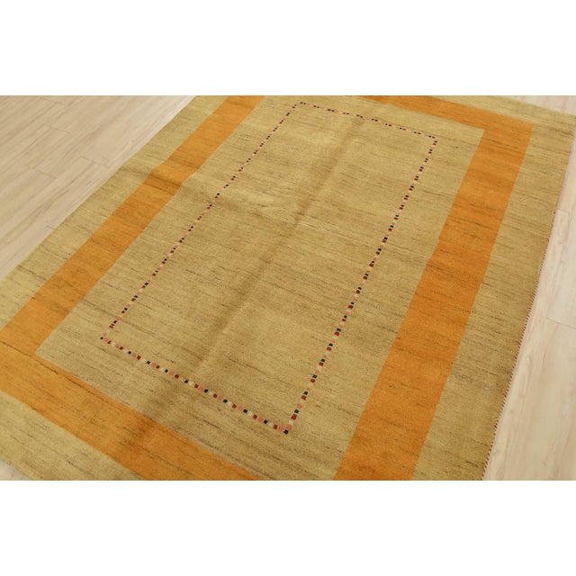 A contemporary Gabbeh rug hand-knotted with an all-wool pile on a cotton foundation. This area rug features a solid beige...