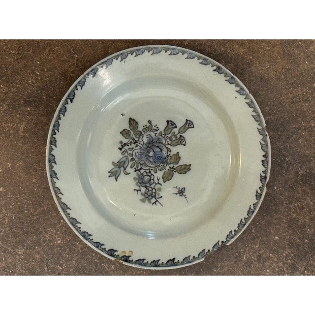 Dutch Delft plate painted in polychrome with a central floral spray in soft blue, green, and manganese tones, surrounded...