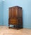 A solid oak cabinet dating to the 1940s, with a warm tone and simple panelled doors. The upper section opens to two glass...
