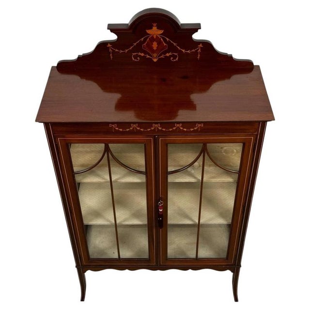 An elegant early 20th-century English display cabinet, finely crafted from mahogany and distinguished by delicate...
