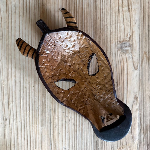 A striking vintage hand-carved wooden zebra mask featuring bold graphic striping and an elongated sculptural form. Crafted...