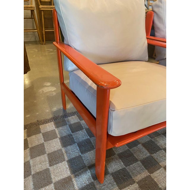 Pair orange lacquered open frame armchairs with new buff leather cushions. Reddish-orange finish on solid hardwood thin...