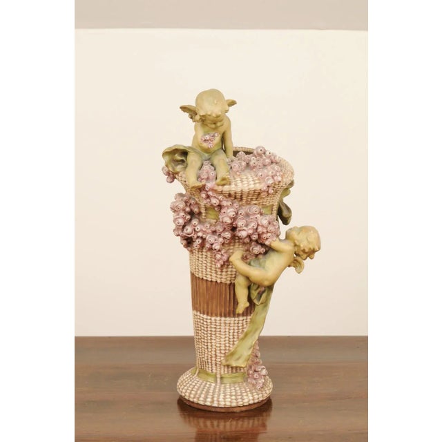 A French Napoléon III period painted terracotta vase from the mid-19th century, with cherubs playing among pink roses....