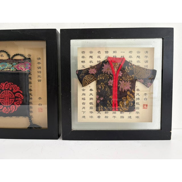 Vintage pair of Asian shadow boxes featuring miniature textile pieces set against printed calligraphy backgrounds. One...