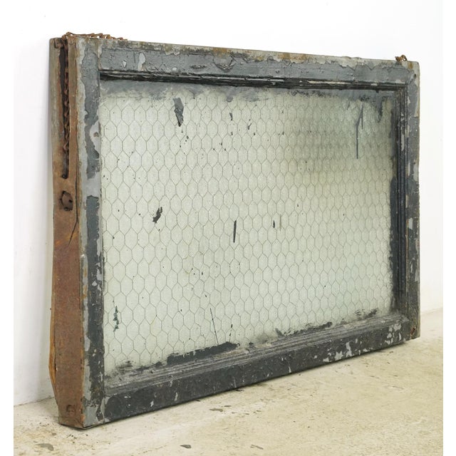 Reclaimed rectangular shaped window with a wood frame, steel sides, and a clear wormy chicken wire glass pane. It was...
