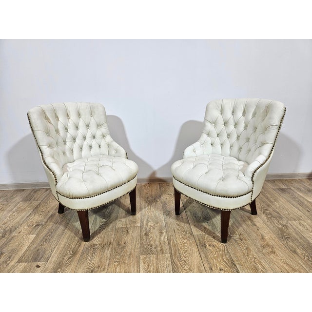 Exclusive pair of Chesterfield armchairs from the 1960s. Upholstered in genuine leather with deeply quilted buttons,...
