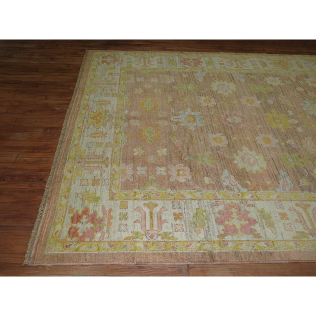 One of a kind wool Turkish Oushak Rug with citrus and pastel accents on a soft brown field. Measures: 8'4'' x 11'2''.