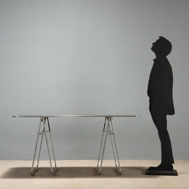Table with chromed metal trestles, laminate top. This piece is attributed to the mentioned designer/maker. It has no...