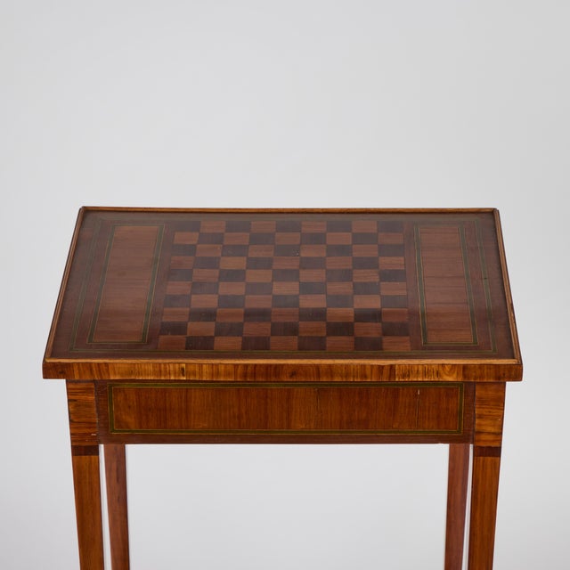 A charming side table with inlaid checkerboard top in burled walnut and poplar that features a lower shelf, inset leather...