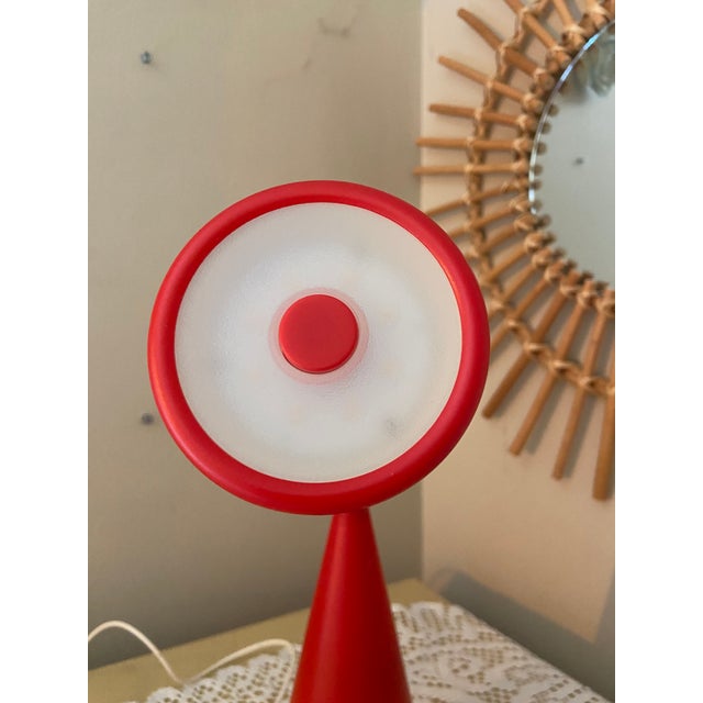 A distinctive IKEA FRYEBO table lamp in vibrant red, featuring an unusual sculptural silhouette, a conical base and a...