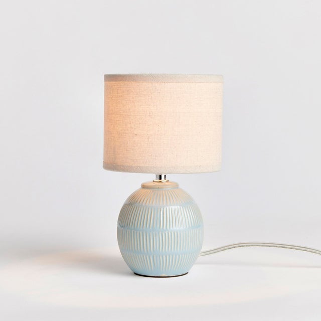 With a petite ceramic body and a soothing sage glaze, this lamp adds warmth to any setting. Topped off with a natural...