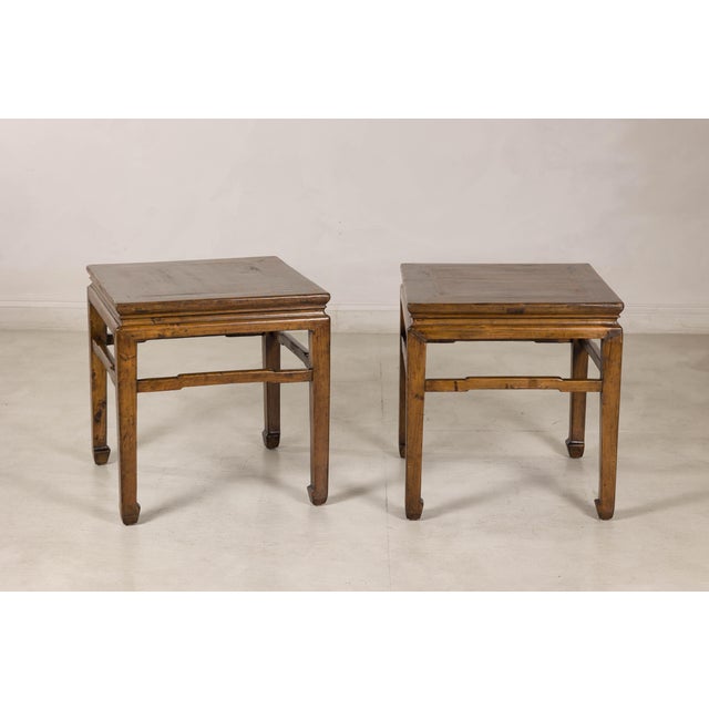 This pair of vintage Chinese side tables features a handsome square form, warm brown wood finish, and details inspired by...