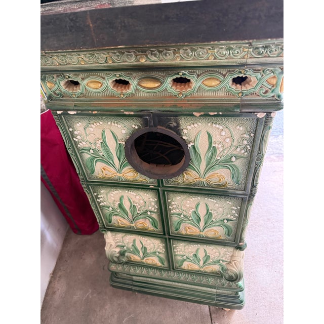 Majolica tiled parlor stove, the body sheathed in green and cream glazed tiles molded with an Art-Nouveau lily-of-the-...