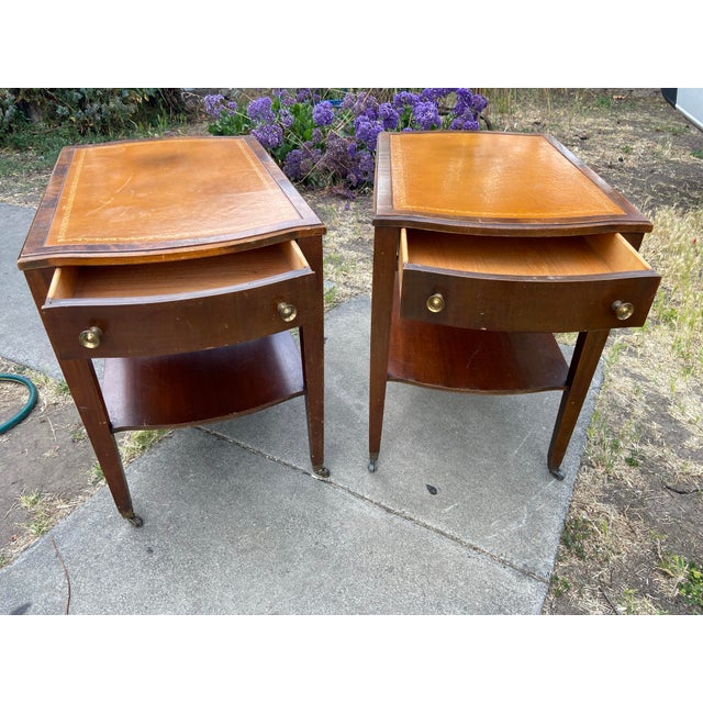 This vintage pair of mid-century mahogany end tables exudes traditional style with their antique finish and leather...