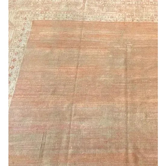 This antique Oushak rug has a plain shaded terracotta field, in a broad ivory border of terracotta and light brown linked...