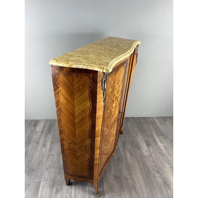 An elegant Louis XV style cabinet with marquetry veneer and rich floral decoration. The front features two wide, curved...