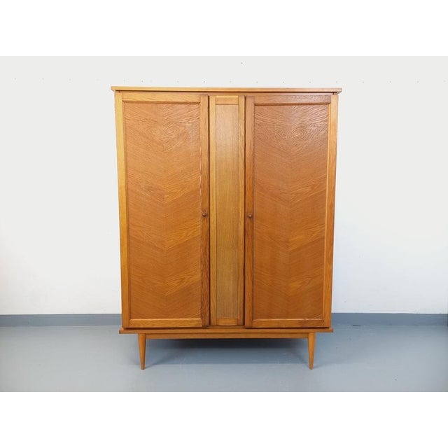 Vintage 1960s oak wardrobe with splayed legs and ample storage: two sliding doors with a hanging rail and three shelves....