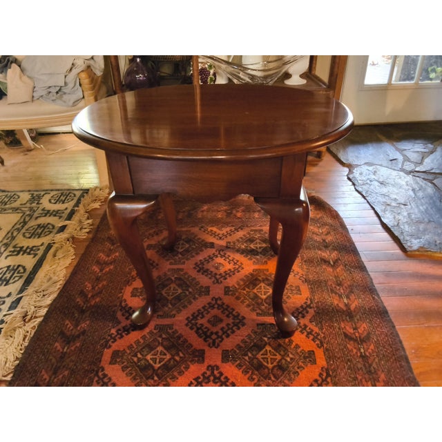 Elevate your living space or bedside with this classic Queen Anne style oval end table by the renowned American...