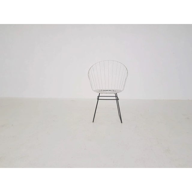 This is a D. Dekker wire chair from Tomado with black metal frame and white metal wire seating.