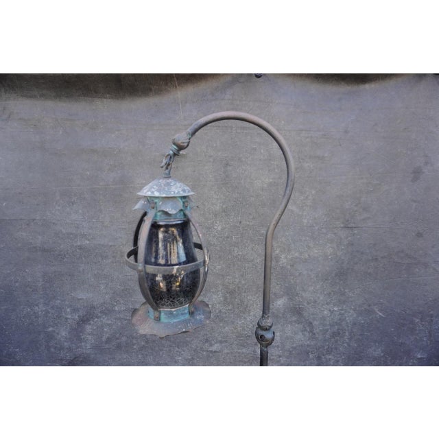 Rustic wrought iron hanging lantern floor lamp, circa 1920s, featuring a beautifully aged hand-forged form with an elegant...