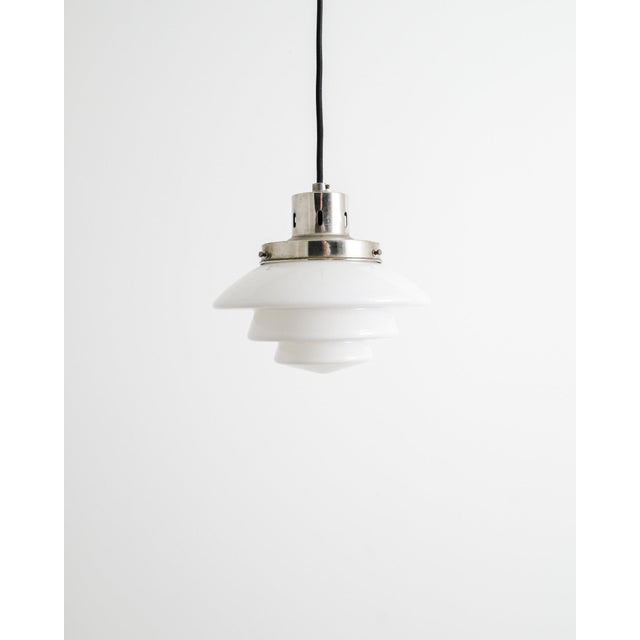 A rare and early finnish mid century ceiling pendant lamp model "1612" in patinated chrome with a white original opaline...