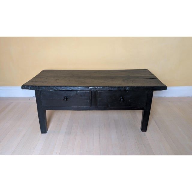 A beautifully timeworn primitive coffee table featuring a richly aged black painted surface and hand-built solid wood...