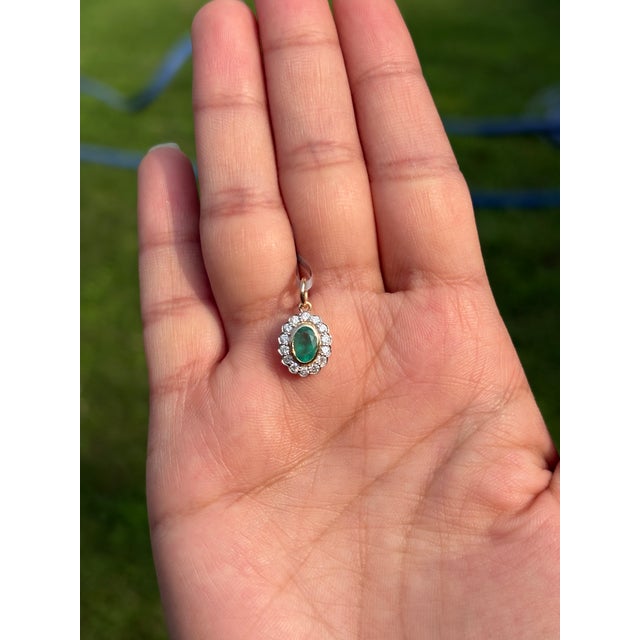 This victorian-inspired floral pendant features one vibrant oval Zambian emerald weighs approximately 0.53 carats, set in...