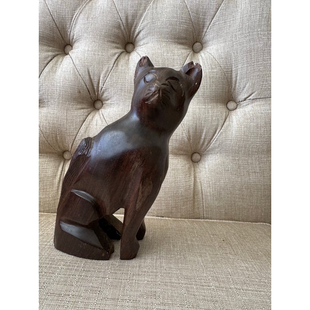 Hand-carved wooden cat figurine with a smooth, sculptural silhouette and rich dark brown finish.