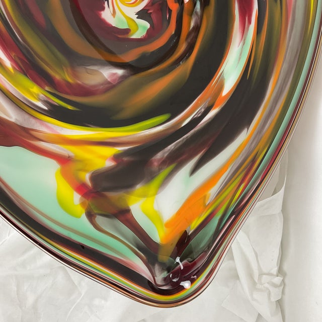 A striking hand-blown Murano glass centerpiece showcasing an expressive vortex design, alive with richly layered tones of...