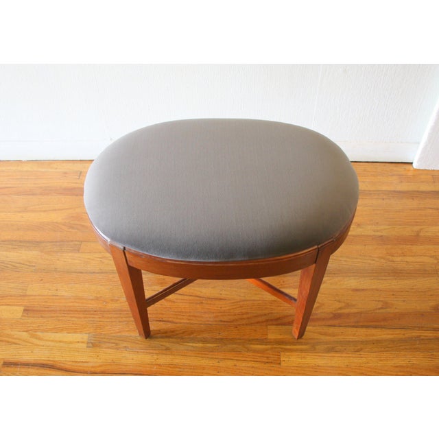 This is a mid century modern oval ottoman with a newly upholstered elephant gray velvet top and solid wood cross base with...