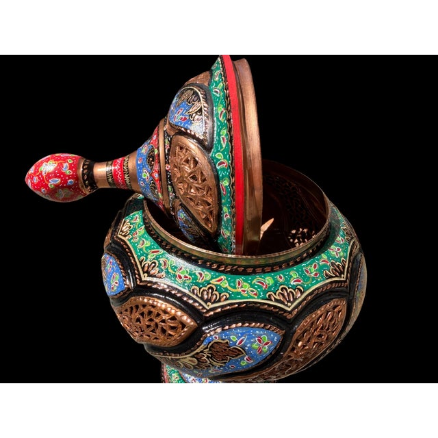 A vintage Turkish copper covered urn with a rounded pedestal form, tall finial lid, and hand-painted decoration...