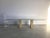 Beautiful trestle shaped travertine and brass dining table with a large oval beveled glass top. The table was made by...