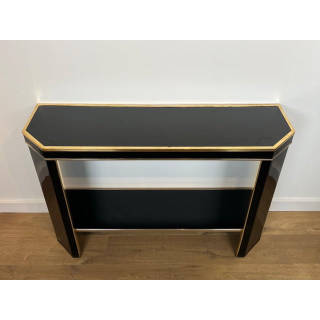 This beautiful console table is made of black lacquered wood and gilded metal. It is a French work by Jean-Claude Mahey....