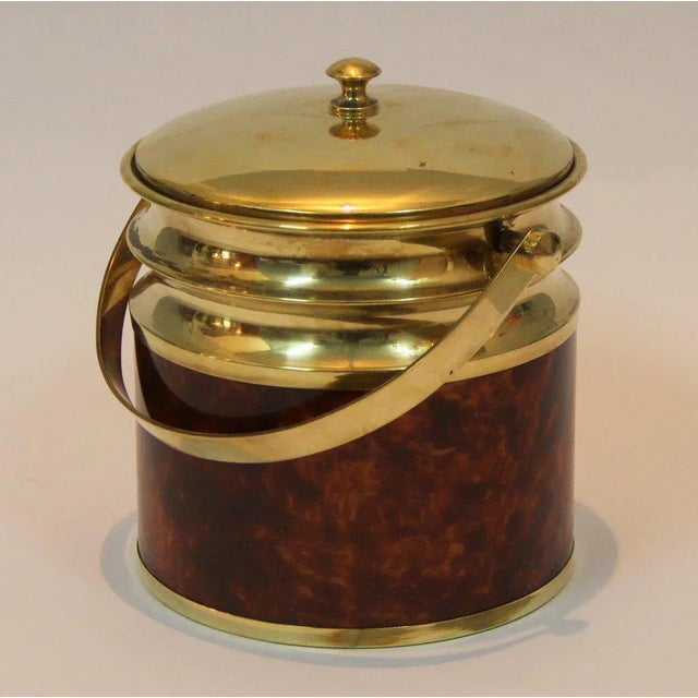 This wine cooler is made from brass and acrylic glass in a wood effect with an interior in aluminum.