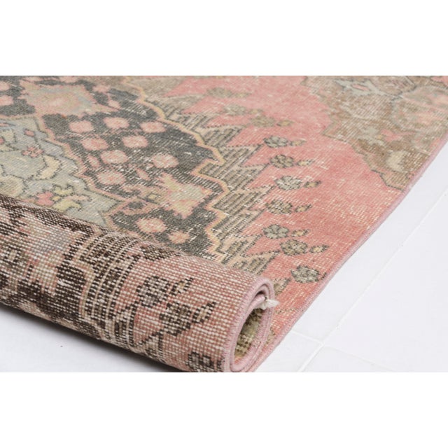 This is a vintage Turkish Oushak rug from the Mid 20th Century. The piece was hand-knotted.