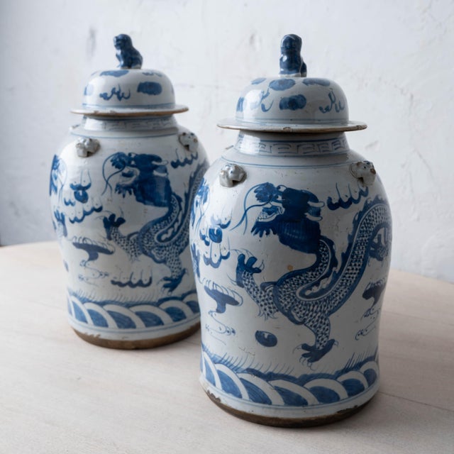A pair of Chinese blue and white glazed stoneware jars, each with a domed lid surmounted by a seated Buddhist lion, or foo...