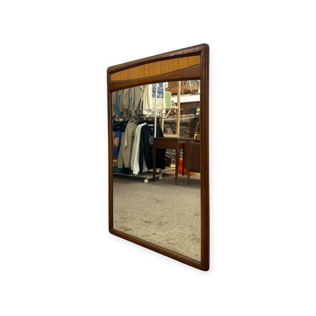 This Mid-Century Modern rectangular wall mirror features a softly rounded solid wood frame with a warm, rich grain finish....