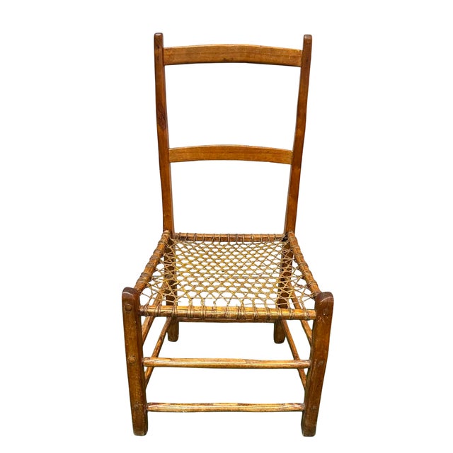 Charming vintage rustic side chair featuring a simple handcrafted wood frame with a tall ladder back and a hand-woven cord...