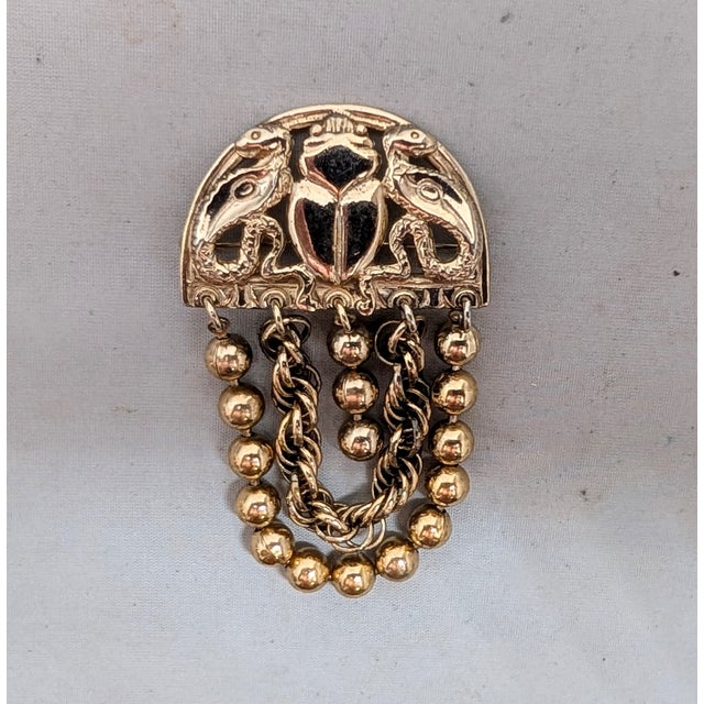 1970s goldtone half moon top with scarab in the middle a serpent on either side with ball and chain looped sections with a...