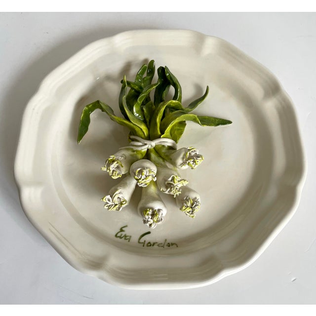Late 20th century Canadian studio pottery plate by Eva Gordon, featuring a beautifully modeled trompe-l’œil bundle of...