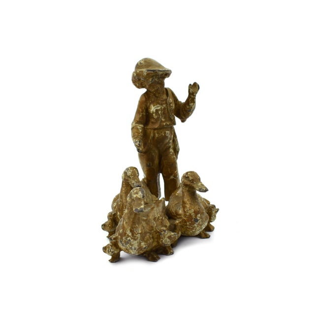 This delightful figurine depicts a young boy interacting with three ducks. Crafted from cast metal and finished in a warm,...