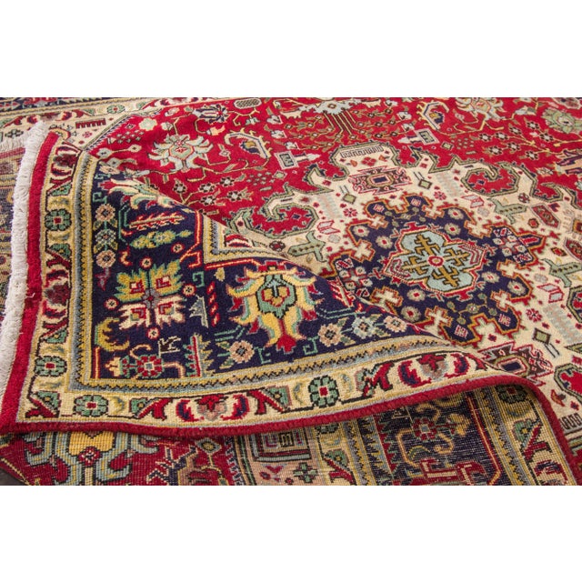 Beautiful vintage Persian Tabriz hand-knotted wool rug. This rug has a red field with multicolored accents featuring a...