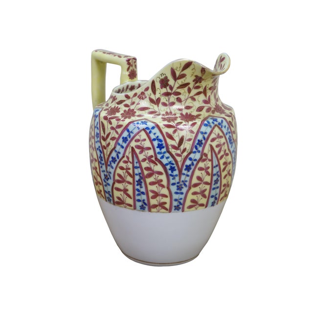 Antique porcelain pitcher featuring a stylized floral chintz pattern in blue / red / yellow enamels Dimensions: 7.5" x 6"...