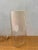 A clear glass cylinder open at the base, with a conical internal diffuser in ivory-colored glass and an exposed bulb on a...